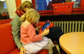 Erziehungsberechtigte Person mit einem Kind und einem Tablet