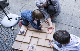Zwei Kinder und ein Erziehungsberechtigter nutzen programmierbares Spielzeug für Kinder